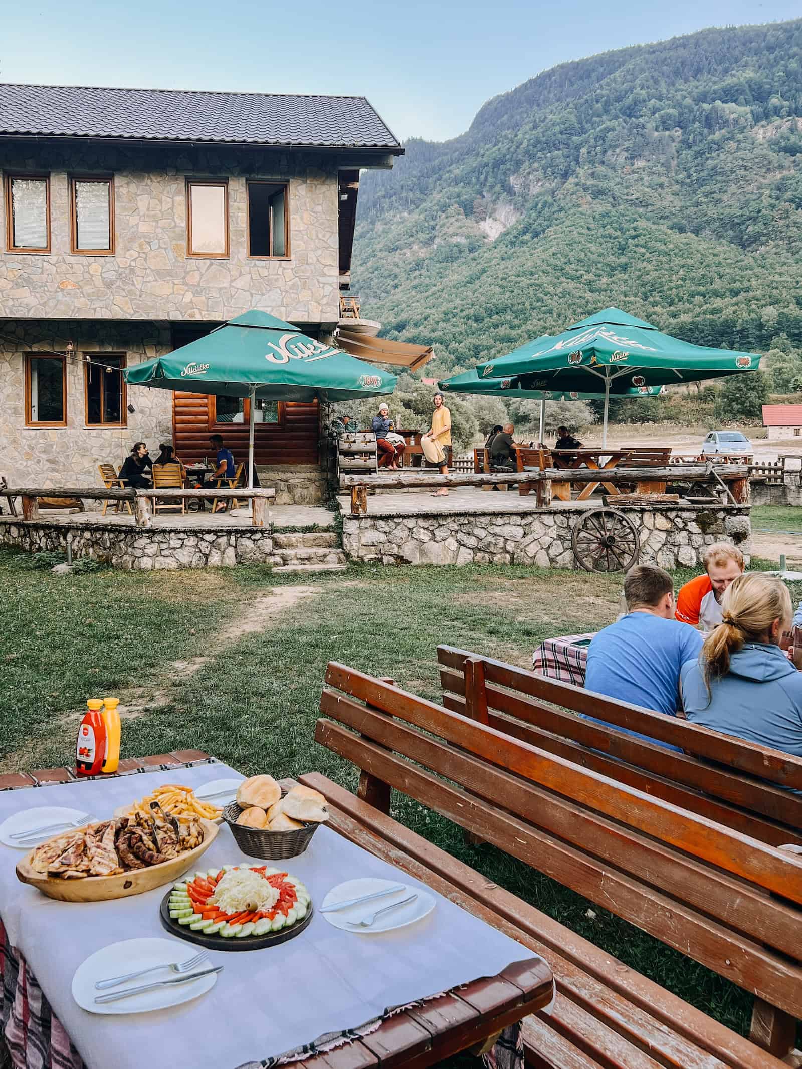 Gedeckter Tisch mit Brot und Grillgerichten auf der Terrasse des Gästehauses in Vusanje